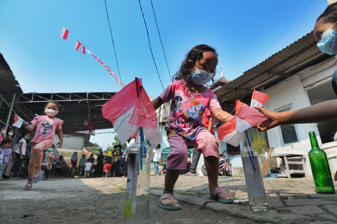 Anak-anak mengikuti lomba memasukkan bendera ke dalam boto saat peringatan HUT Kemerdekaan RI ke-76 di Benda Baru, Pamulang, Tangsel, Selasa (17/08/2021). Di sejumlah kawasan pinggiran Jabotabek warga tetap melaksanakan peringatan HUT kemerdekaaan RI walau masih dalam status PPKM Level 4