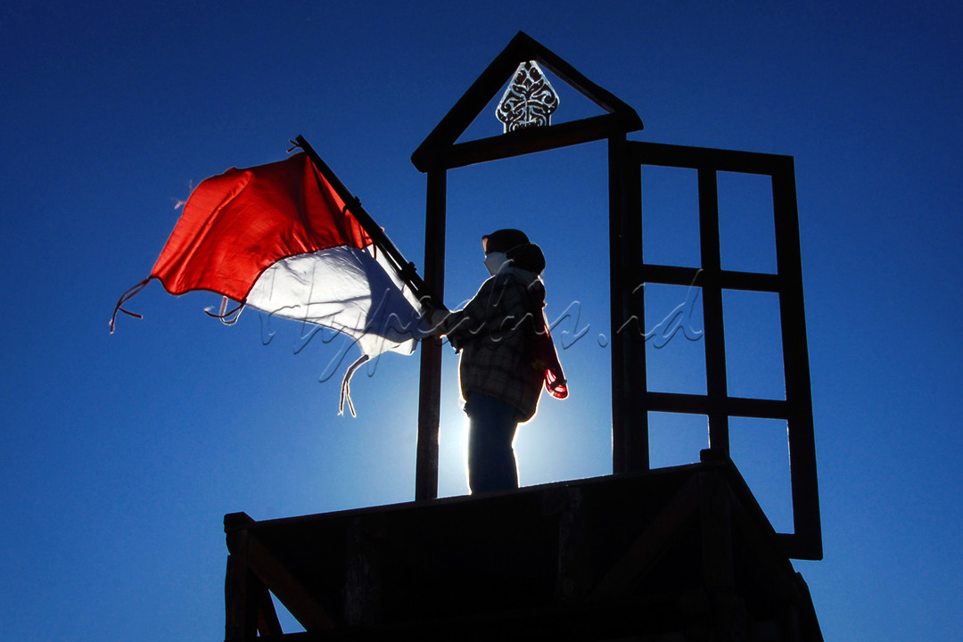 Ainun mengibarkan bendera Merah Putih pagi hari di taman wisata milenial Panenjoan Gunung Windu Pangalengan Jawa Barat.
