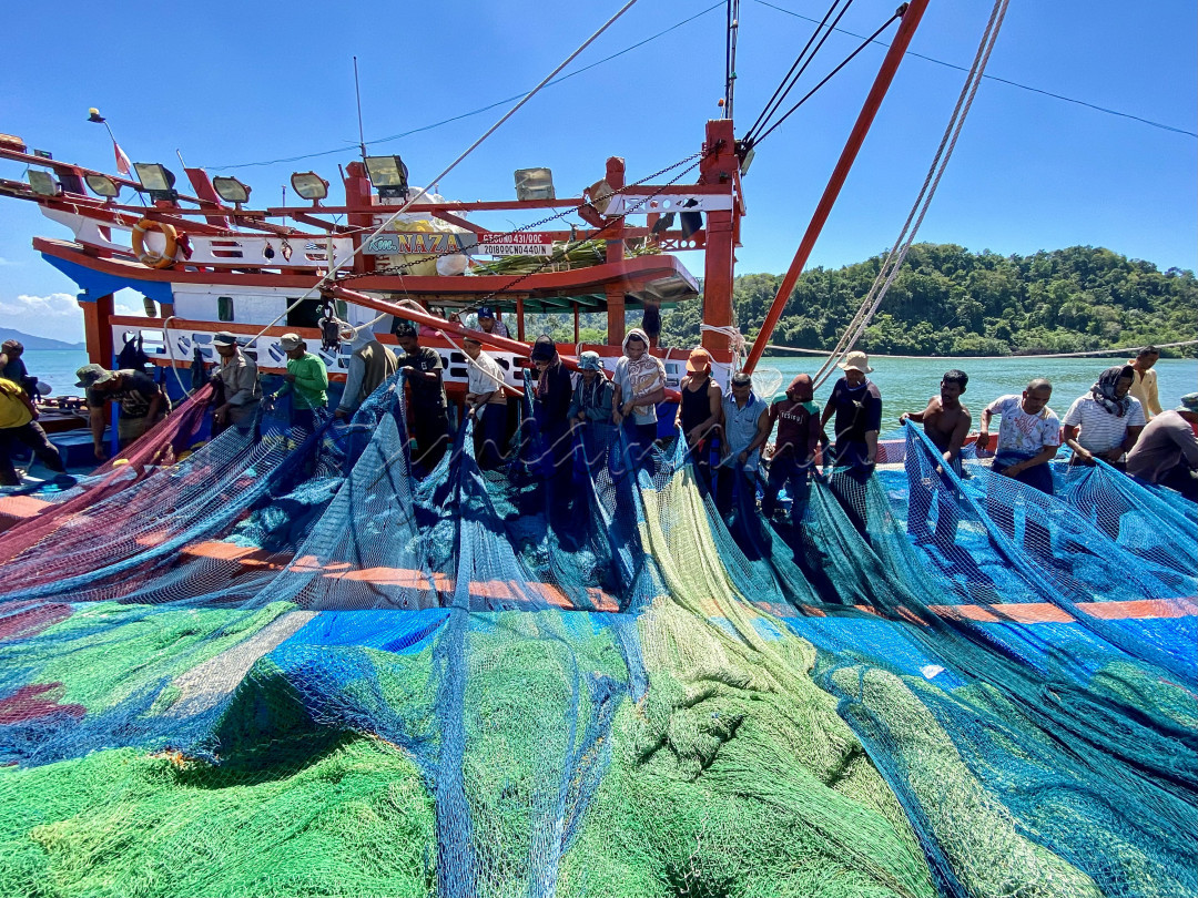Para nelayan sedang merapikan jaring tangkap ikan ke atas kapal kayu di dermaga Pulo Aceh, Aceh Besar, Provinsi Aceh. Meski ditengah kondisi Pandemi COVID-19, nelayan di ujung barat Indonesia tetap melaut untuk kebutuhan ekonomi keluarga.
