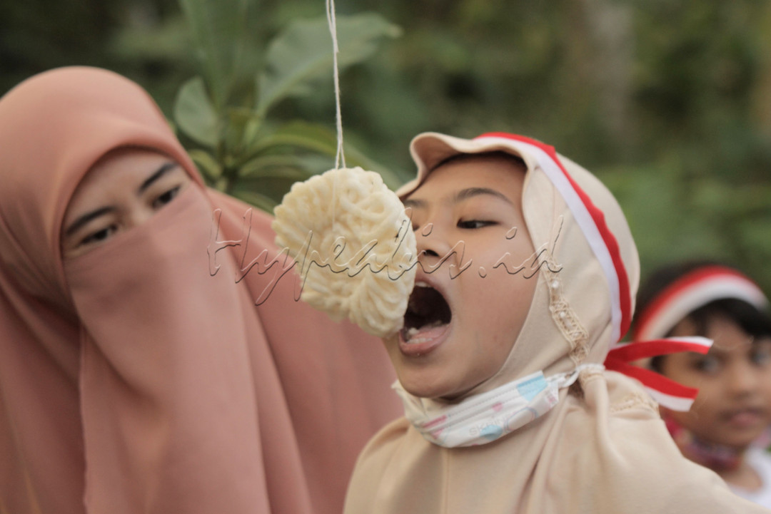 Seorang ibu memberi semangat putrinya saat mengikuti lomba makan krupuk dalam perayaan HUT RI ke 76 di Perum Lebo Permai Warung Asem Kab batang, 18 Agustus 2021