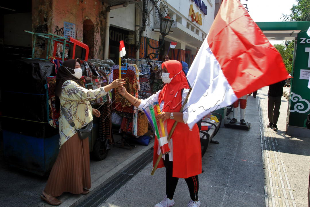 Memperingati HUT Ke-76 RI, warga membagikan bendera sebagai tanda dukungan semangat kepada pedagang kaki lima (PKL) di Jalan Malioboro, Kamis, 5 Agustus 2021. Dukungan moril sangat dibutuhkan para PKL agar dapat terus bersemangat mencari rezeki demi perbaikan ekonomi walaupun di masa perpanjangan PPKM Level 4 di DIY.