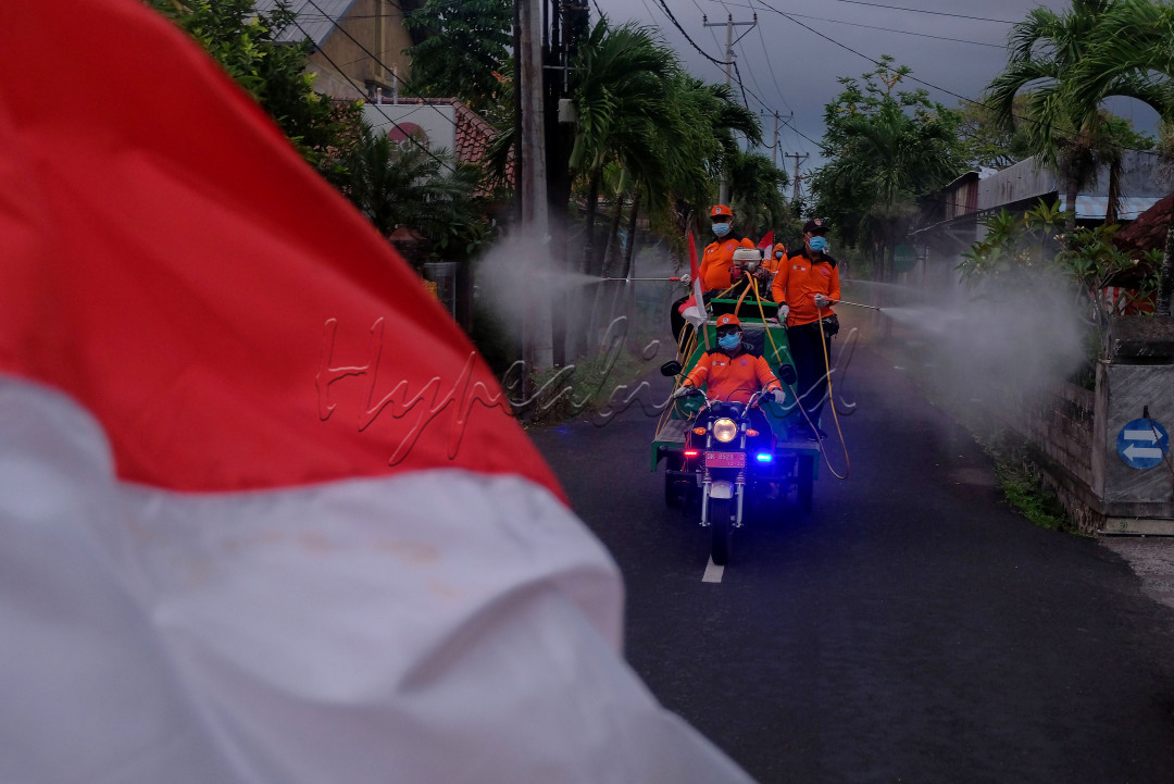 Tim Reaksi Cepat dan Satgas COVID-19 Tangguh Dewata menyemprotkan cairan disinfektan dengan membawa bendera merah putih dengan diiringi alunan lagu perjuangan dalam perjalanan berkeliling Desa Sumerta Kelod, Denpasar, Bali, Selasa (17/8/2021). Kegiatan yang dimulai pada pukul 06.00 - 08.00 WITA tersebut untuk merayakan HUT Kemerdekaan ke-76 Republik Indonesia pada masa pandemi COVID-19 sekaligus upaya pencegahan penyebaran COVID-19 yang jumlah kasusnya masih tinggi di kawasan itu. 