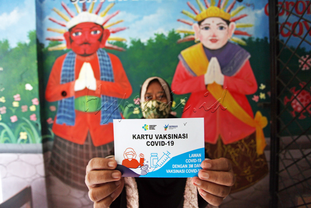 Warga menunjukan kartu vaksin usai mengikuti vaksinasi massal yang diselenggarakan di SDN 01 Petamburan, Jakarta Pusat, Jumat (23/7/2021). Vaksinasi yang diselenggarakan oleh Polda Metro Jaya ini bagi warga petambutan dilakukan dengan memberikan kuota sebanyak 250 vaksin merek sinovac.