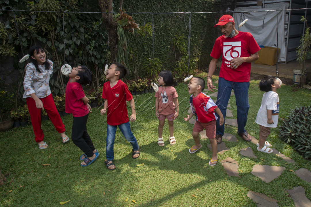 Seorang kakek bersama cucu-cucunya mengikuti lomba makan kerupuk untuk memeriahkan hari ulang tahun (HUT) ke-76 kemerdekaan Republik Indonesia (RI) di salah satu rumah di Cimanggu, Bogor, Jawa Barat, Selasa (17/8/2021). Lomba-lomba dalam rangka memeriahkan HUT RI tetap mereka lakukan secara internal di lingkungan keluarga mereka untuk mencegah penularan COVID-19.