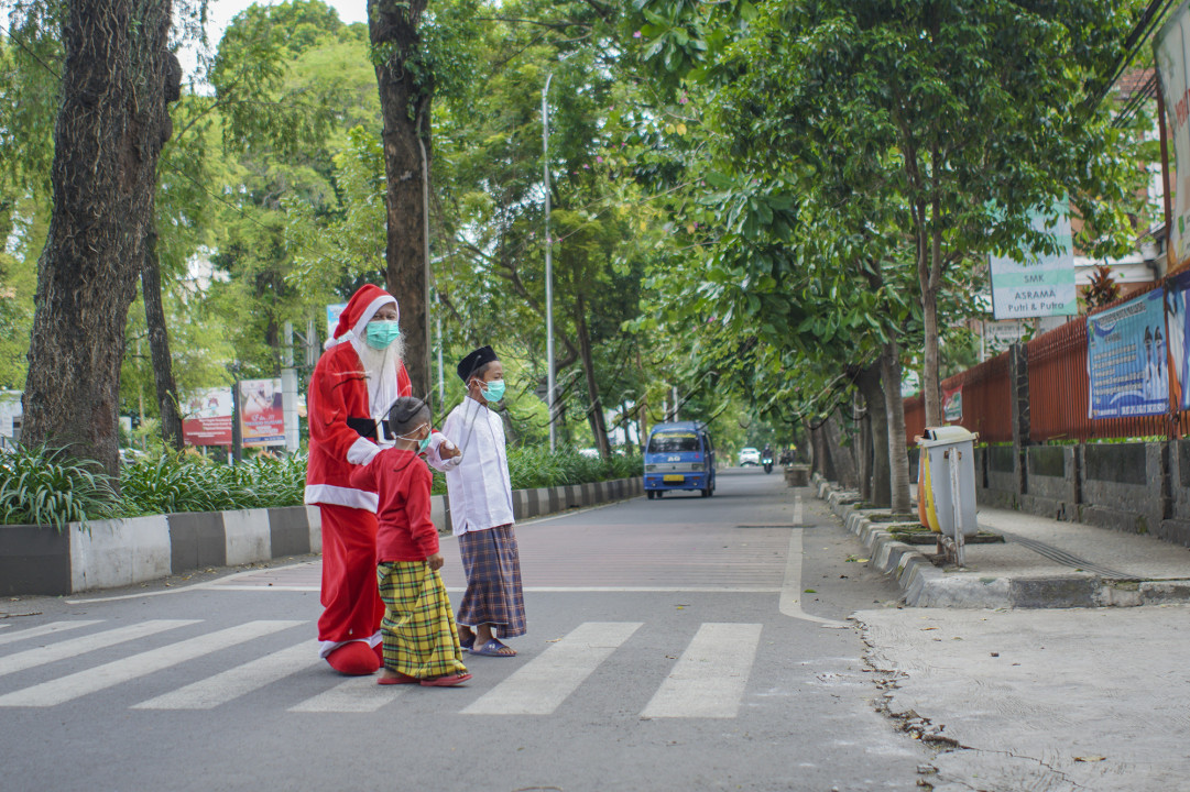 Seorang Santa Clause menyeberangkan 2 Anak Muslim yang akan berangkat Sholat Jumat saat perayaan Natal 2020 yang yatuh tepat pada hari Jumat