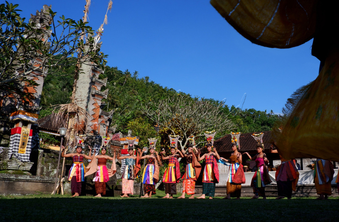 Penari rejang sedang malakukan tarian persembahan, dengan kain warna warni dan hiasan kepala yang unik.