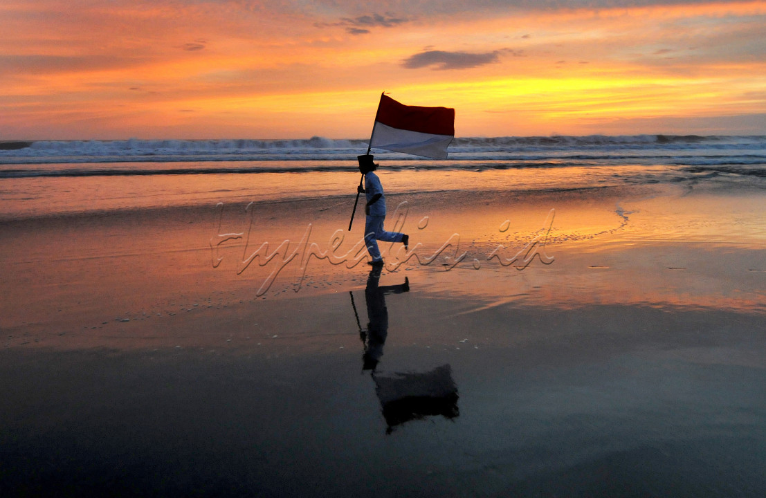 Pelajar SMP membawa bendera merah putih saat melakukan pengambilan video dalam rangka lomba tiktok di sekolahnya di di kawasan Pantai Pasut, Tabanan, Bali, Sabtu (04/09/2021)