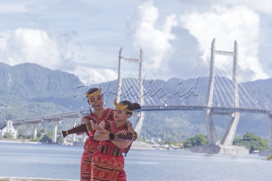 Sejumlah gadis membawakan tari tradisional dengan latar belakang Jembatan Merah Putih di Kota Ambon, Provinsi Maluku pada 29 November 2021.