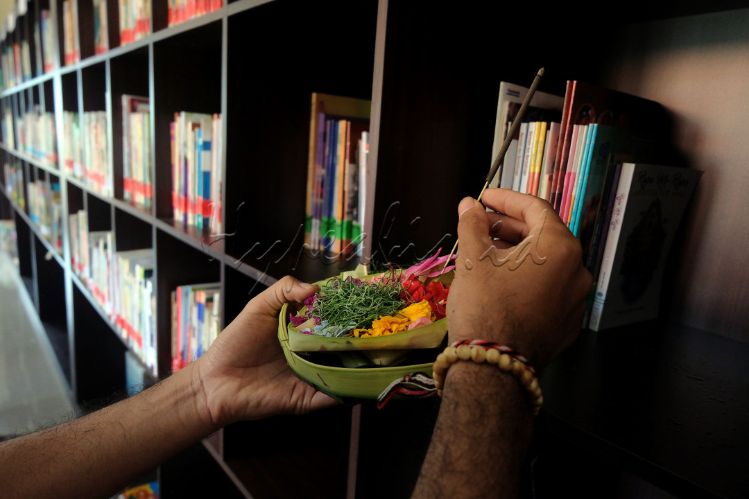 Umat Hindu menghaturkan sesajen saat melakukan penyucian terhadap ribuan buku dalam persembahyangan Hari Saraswati di Perpustakaan Sabha Widya Sradha, Desa Sumerta Kelod, Denpasar, Bali, Sabtu (28/8/2021). Ribuan buku di perpustakaan desa tersebut diupacarai saat Hari Saraswati yaitu hari turunnya ilmu pengetahuan untuk wujud syukur kepada Tuhan YME sebagai sumber dan pencipta ilmu pengetahuan yang telah menganugerahkan kecerdasan bagi umat manusia.