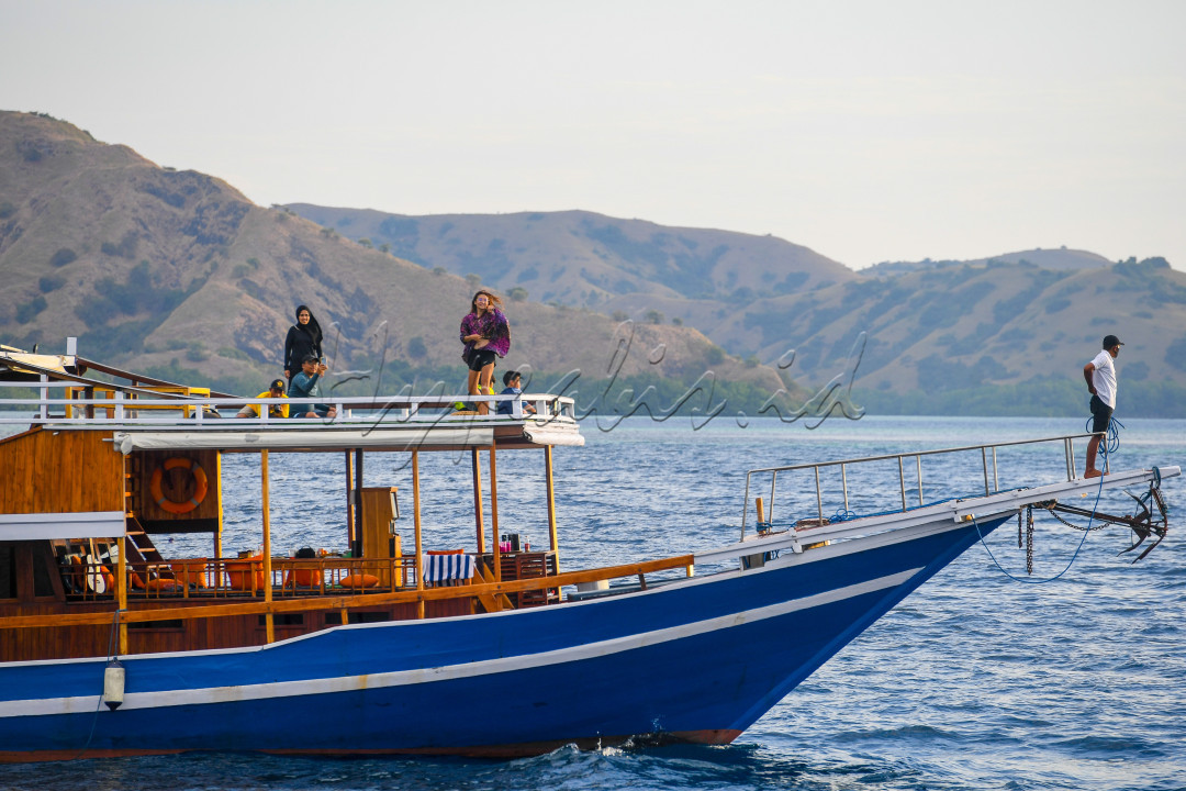 Wisatawan berpose di atas perahu pinisi di Pulau Kalong, Labuan Bajo, Nusa Tenggara Timur