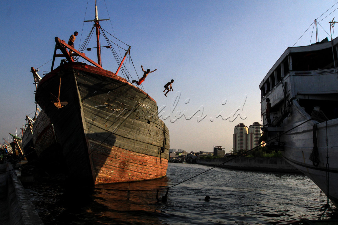 Sejumlah anak melompat dari atas kapal pengangkut barang yang bersandar di dermaga Pelabuhan Sunda Kelapa, Jakarta, Jumat (28/08). Ditengah pandemi Covid-19 sejumlah anak yang tinggal di pesisir melatinh ketangkasan bersama dengan berenang di Pelabuhan Sunda Kelapa. 