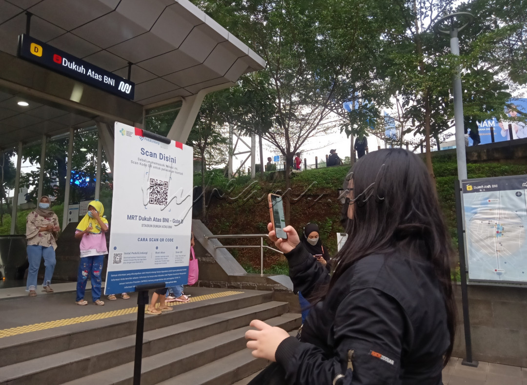 Kewajiban calon penumpang MRT sebelum memasuki stasiun MRT Dukuh Atas BNI, yaitu scan Peduli Lindungi.