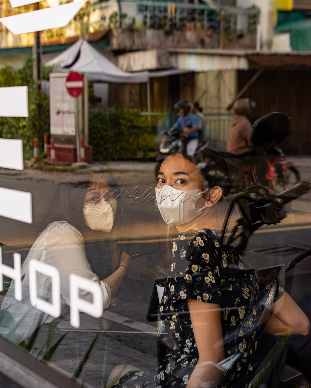 Dua wanita mengenakan masker di era pandemi di kota Medan, terkejut ketika sebuah kamera menangkap gambar spontan ke mereka dari balik sebuah kaca cafe. Berpose seolah - olah menghilangkan keterkejutan mereka sambil menatap datar lensa kamera dari balik refleksi kaca.