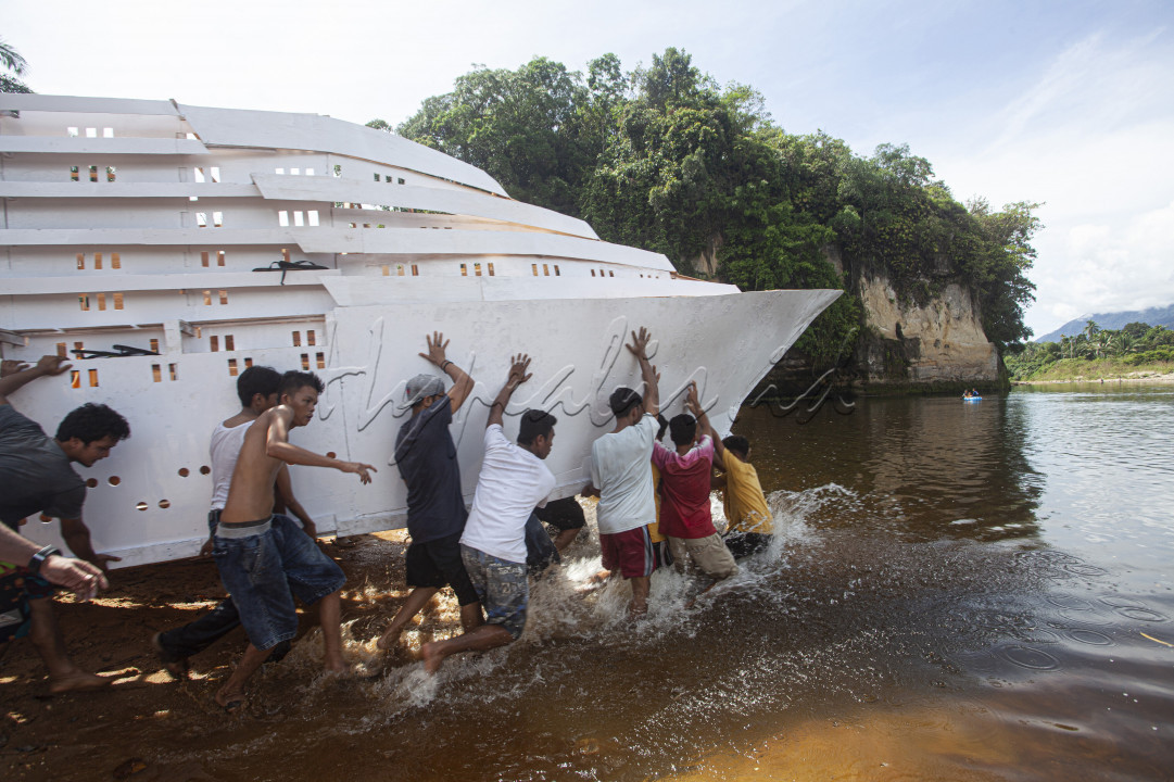 Warga bergotongroyong mengangkat kajang (perahu yang dihias serupa kapal pesiar) saat digelarnya tradisi Bakajang di Sungai Batang Mahek, Nagari Gunuang Malintang, Kabupaten Limapuluhkota, Sumatera Barat, Kamis (5/5/2022). Bakajang merupakan tradisi turun temurun menghias perahu yang dilakukan masyarakat di lima jorong di Nagari Gunuang Malintang selepas Idul Fitri dalam rangka menjalin silaturahmi dan melestarikan adat budaya.