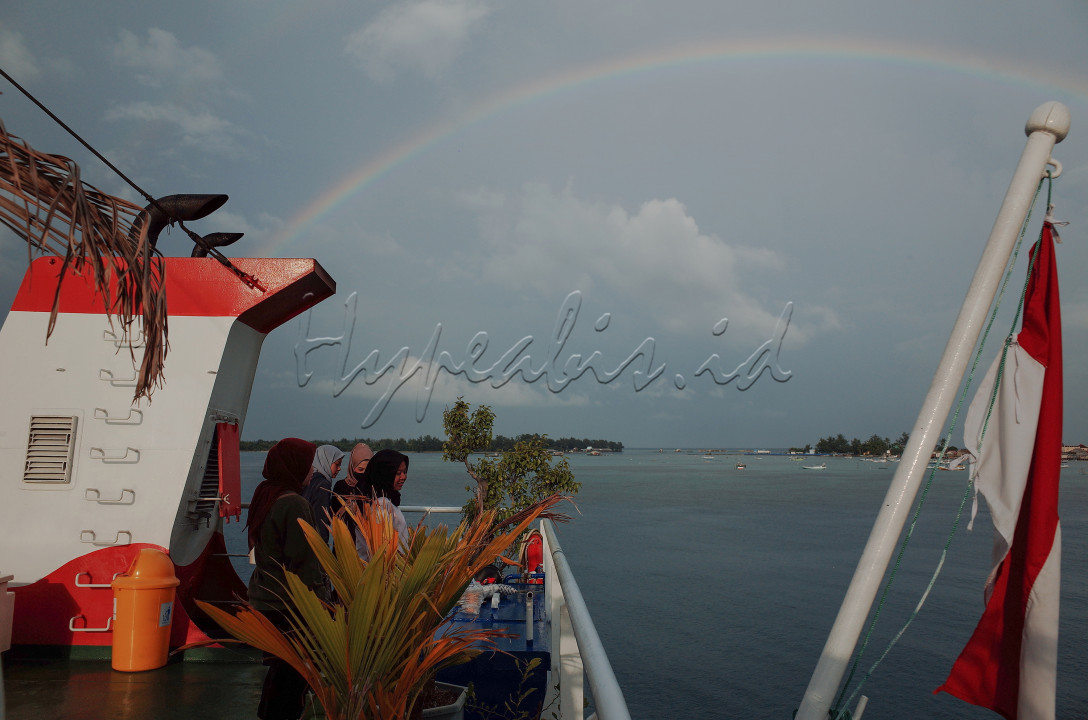 beberapa orang wisatawan domestik menikmati pagi bersama pelangi di atas dek kapal ferry Siginjai sebelum pulang meninggalkan pulau Karimunjawa. kapal penyebrangan ferry Siginjai merupakan salah satu transportasi yang bisa dipilih wisatawan untuk pulang dan pergi ke Taman Nasional Karimunjawa dengan estimasi waktu tempuh 4-5 jam perjalanan.<br />
<br />
lokasi: Pelabuhan Karimunjawa, Jawa Tengah