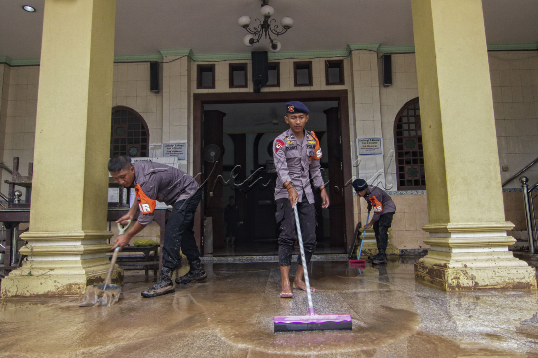 Personil dari kepolisian bergotong royong membersihkan salah satu ruangan Masjid yang terkena banjir bandang di jalan Wahyu Utomo Ngaliyan Semarang.