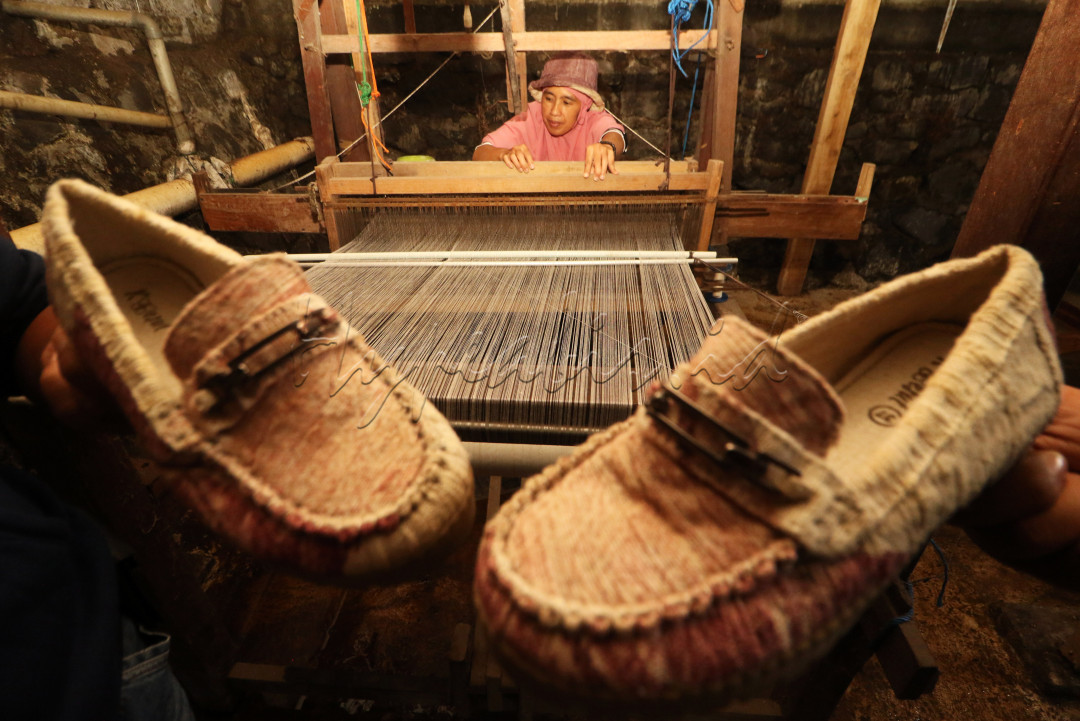 Luh Gede Indrawati, perajin sepatu berbahan sutra kupu-kupu sedang menenun benang sutra di rumahnya di Desa Sentul, Kecamatan Purwodadi, Kabupaten Pasuruan, Provinsi Jawa Timur, Selasa (29/11) siang. Wanita berusia 45 tahun ini sudah tujuh tahun lebih menggeluti usaha kerajinan tersebut.<br />
Berkat inovasi dan keuletannya, sepatu sutra kupu-kupu buatannya mampu diminati sampai mancanegara. Bahkan sepatu tersebut beberapa kali dipamerkan di ajang even internasional. Seperti, even MotoGP Mandalika di Lombok, Nusa Tenggara Barat dan KTT G20 di Bali pada tahun ini.<br />
Selain sebagai ibu rumah tangga, Indrawati merupakan sosok inspirator dalam menjalankan usaha kecil menengah keluarganya. Tak hanya itu, ia juga mengkaryakan para penyandang disabilitas di wilayahnya untuk memajukan usaha tersebut bersama-sama<br />
<br />
