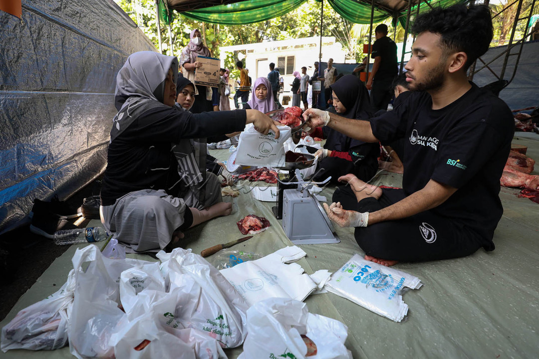 Petugas mengemas daging kurban sebelum dibagikan ke warga