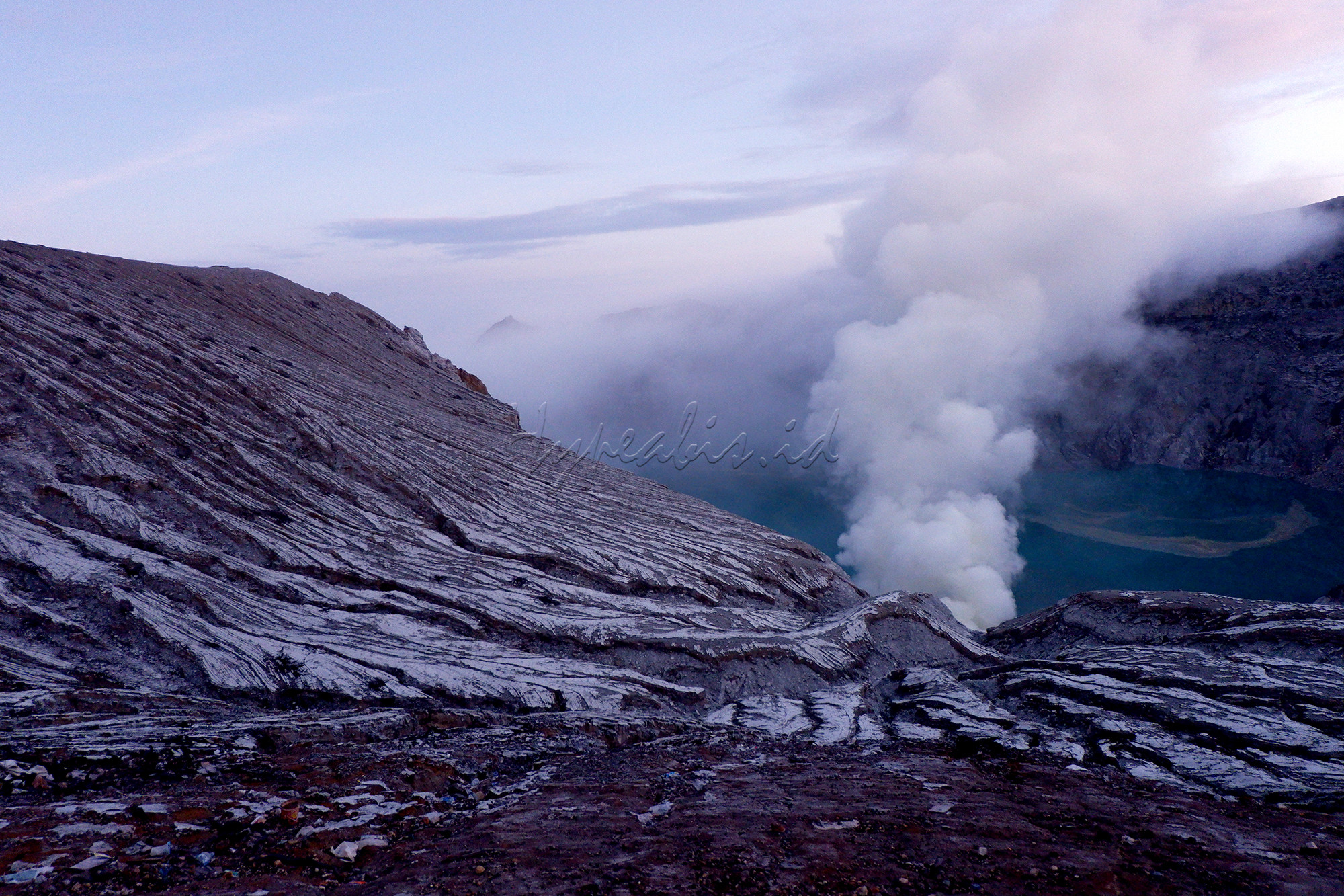 Wisatawan menikmati pagi di kawasan puncak Gunung Ijen, Bondowoso, Jawa Timur. Gunung Ijen berada di kawasan Wisata Kawah Ijen dan Cagar Alam Taman Wisata Ijen dan masih menjadi destinasi wisata populer dan unggulan di Jawa Timur. Kawah Ijen berada di ketinggian 2.368 meter di atas permukaan laut (mdpl). Kawah berdinding kaldera setinggi 300-500m, luasnya sekitar 5.466 hektar. Kawah ini terletak di tengah kaldera terluas di Pulau Jawa. Ukuran kaldera sekitar 20 kilometer. Ukuran kawahnya sekitar 960 meter x 600 meter. Kawah berada di kedalaman lebih dari 300 meter di bawah dinding kaldera. Air kawah itu cukup tenang dan berwarna hijau kebiru-biruan.